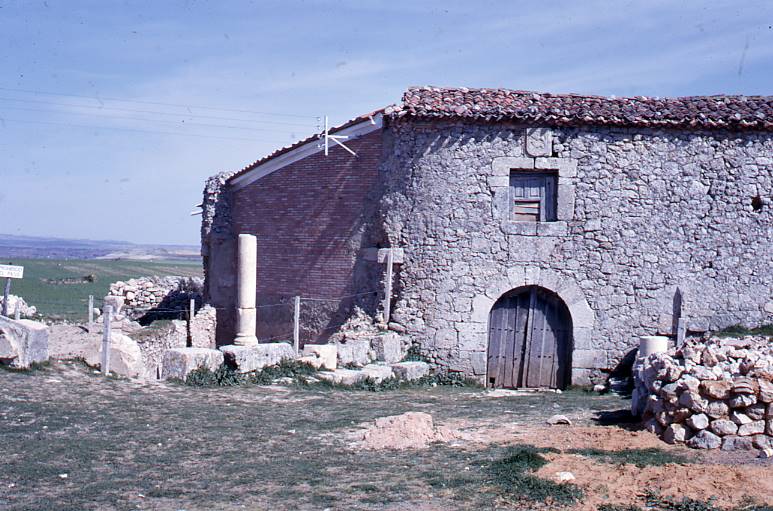 [Vista general de l'edifici conservat en elevació entre les runes de Clunia]